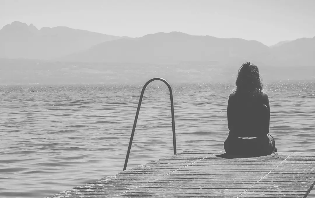 Sad woman sitting at the end of a pier.